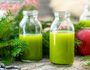 Fichtenzweig, Gläser mit grünem Smoothie, roter Apfel, Holztisch